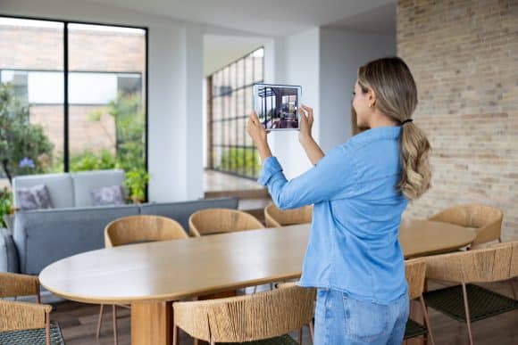 Happy house rental hostess taking pictures of a home using a digital tablet