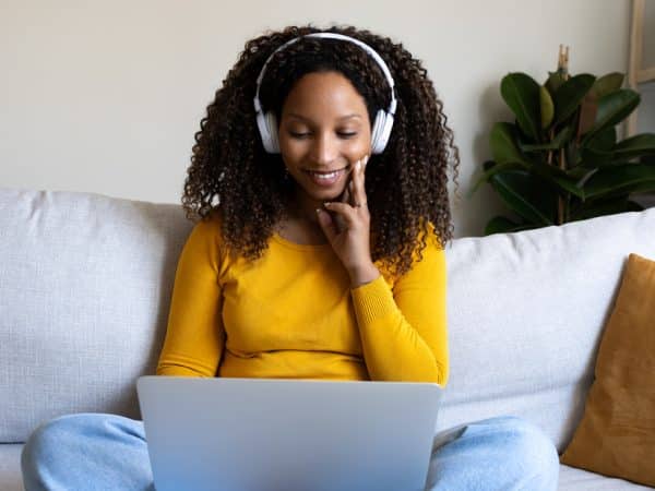 Young woman working from home sitting on the sofa and using laptop